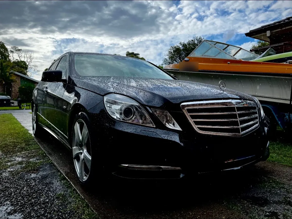 Black Mercedes-Benz E-Class sedan after a hand detail, water beading on the paint